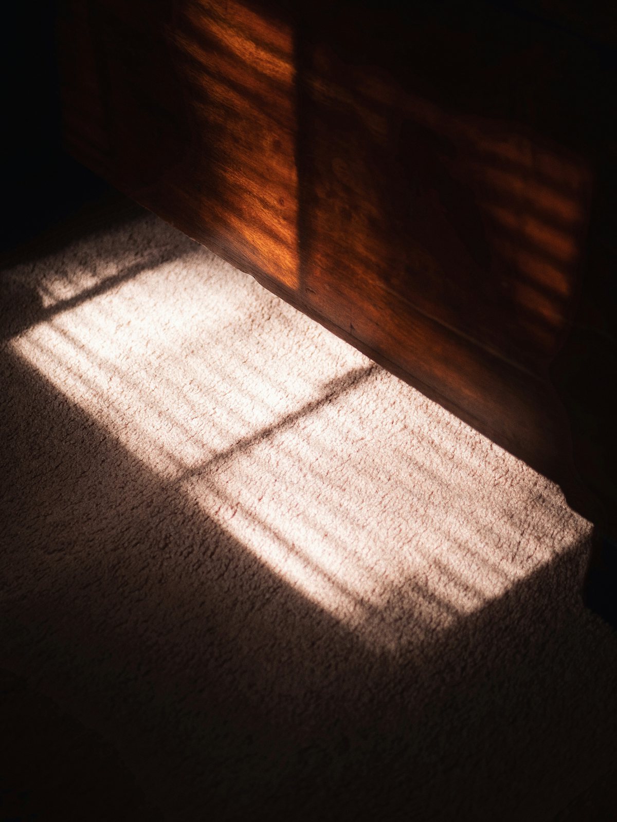 Sunlight falling across a floor through window blinds.