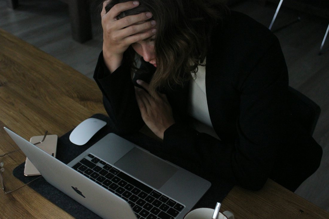 A person sitting at a desk with their head resting on one hand.