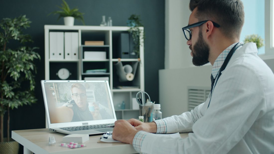 A video consultation in progress on a laptop screen.