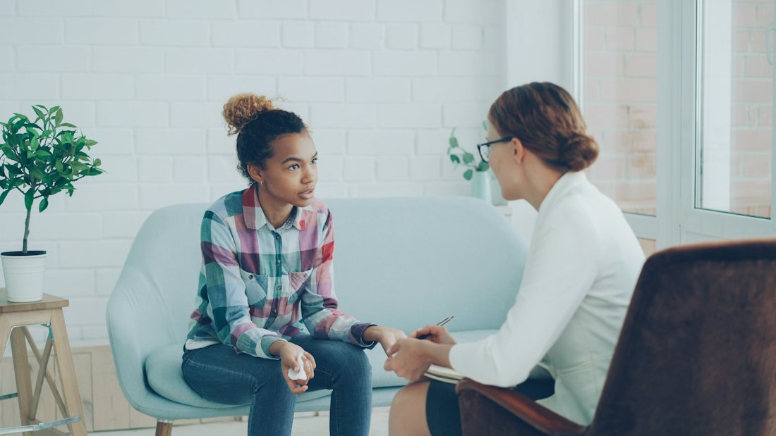 A practitioner and a client talking, seated across from each other.
